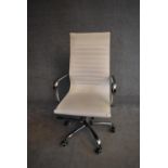 A Charles Eames style swivel office armchair in cream vinyl upholstery. H.110x56cm