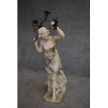 A marble candlestand in the form of an Art Nouveau figure holding a branch with flowers and sconce