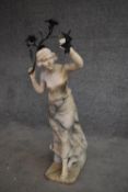 A marble candlestand in the form of an Art Nouveau figure holding a branch with flowers and sconce