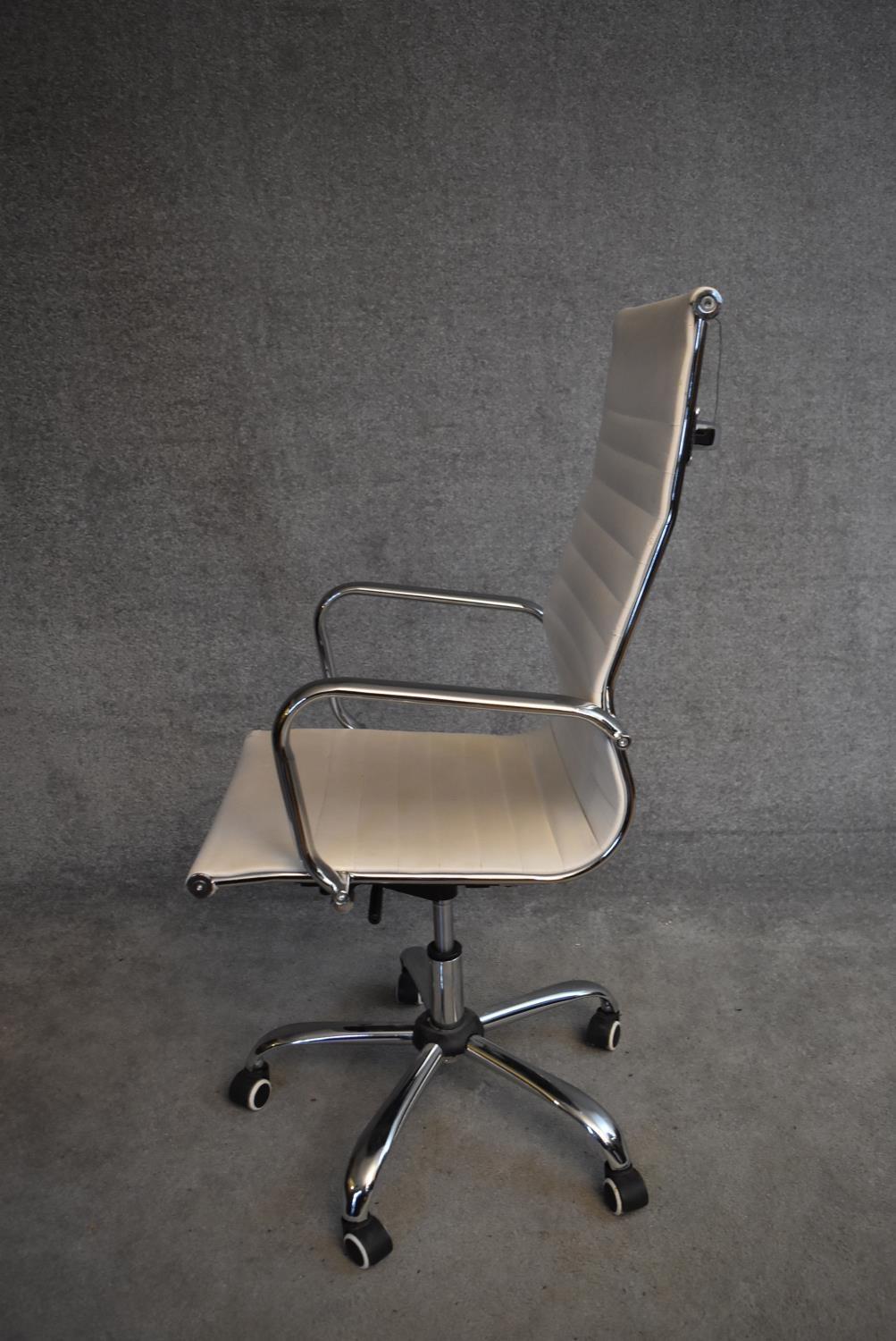 A Charles Eames style swivel office armchair in cream vinyl upholstery. H.114x50cm - Image 2 of 4