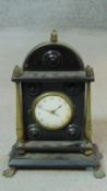 An Regency ebonised and brass mantle clock on four lion paw feet with brass columns and acorn