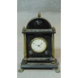 An Regency ebonised and brass mantle clock on four lion paw feet with brass columns and acorn