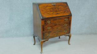 A Georgian style figured walnut bureau with fall front revealing fitted interior above three