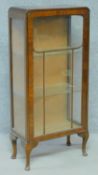 A mid 20th century Art Deco style walnut display cabinet with glazed panel door enclosing glass