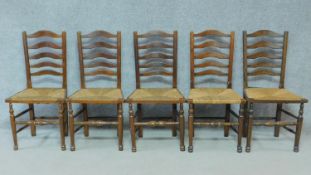 A set of five antique oak ladder back dining chairs with woven rush seats on turned stretchered