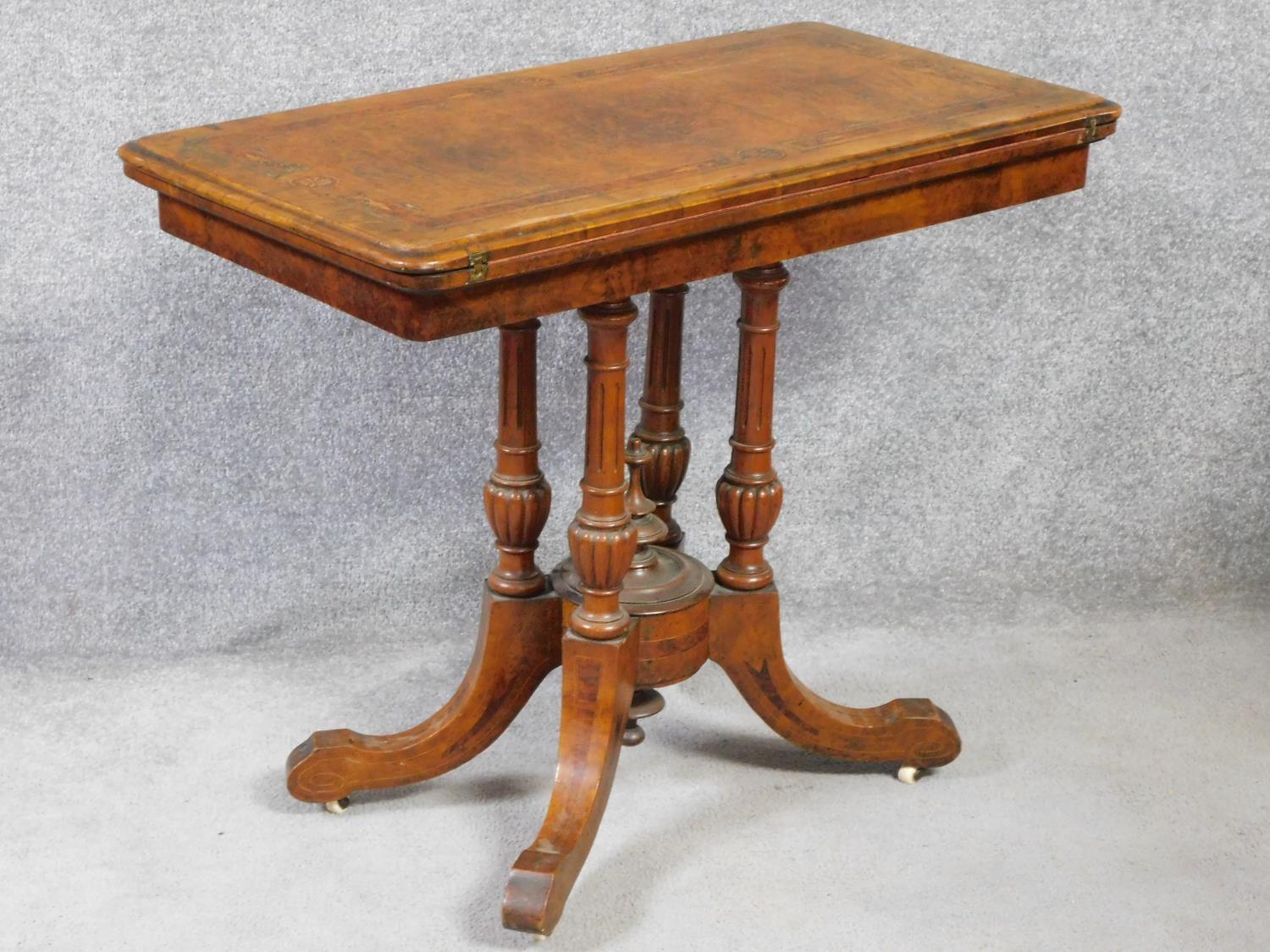 A Victorian burr walnut and satinwood inlaid card table with foldover top on quadruped column