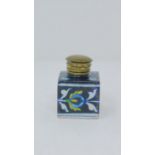 An antique glazed ceramic perfume bottle with brass lid, decorated with a stylized floral and