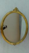A giltwood wall mirror with foliate cresting and oval plate. 83x110cm