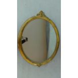 A giltwood wall mirror with foliate cresting and oval plate. 83x110cm