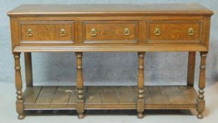 A Georgian style country oak sideboard with three frieze drawers raised on turned supports united by