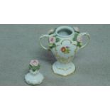 A German porcelain two handled lidded urn with hand painted floral motifs and sculpted porcelain
