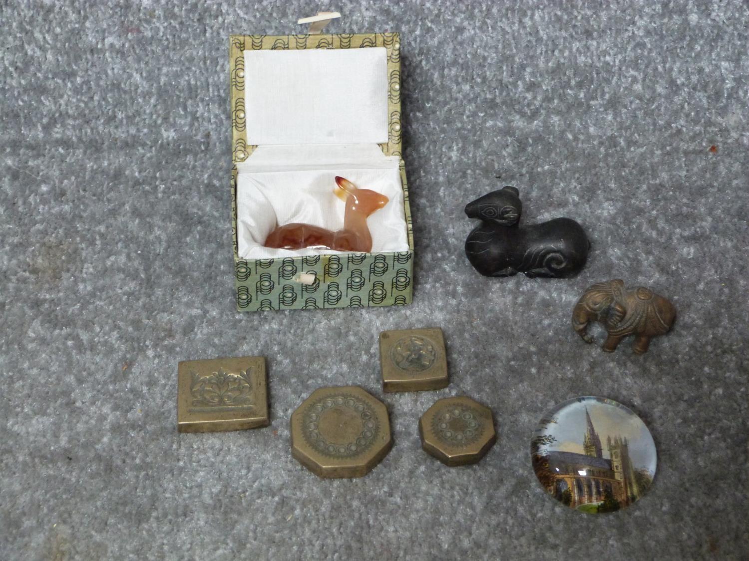 A collection of metal items and a carved carnelian deer. Including a bronze scroll weight in the