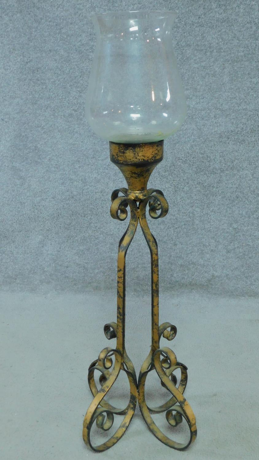 A cast iron floor standing candle holder with glass bowl. Four scrolling feet with openwork