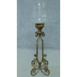 A cast iron floor standing candle holder with glass bowl. Four scrolling feet with openwork