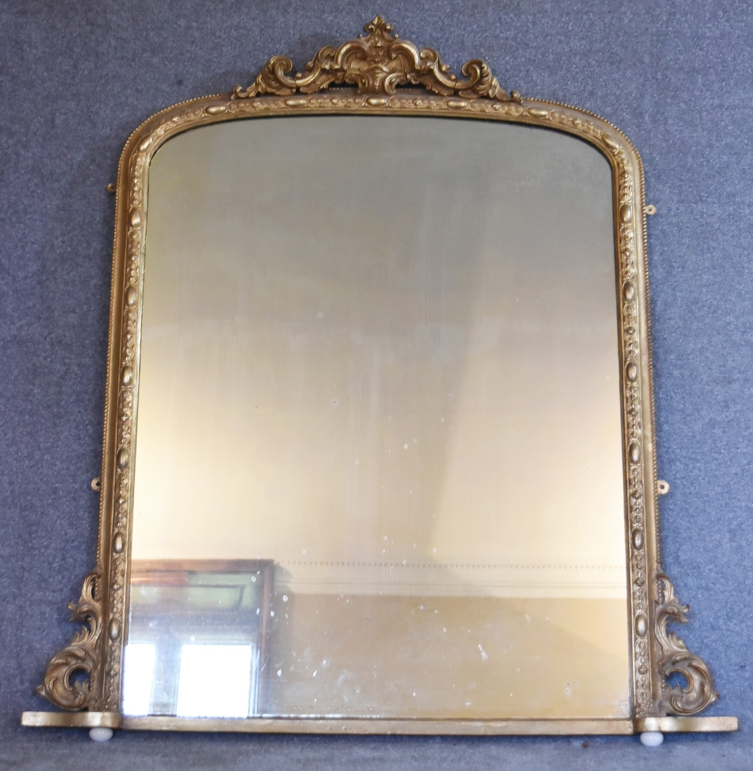A 19th century carved giltwood overmantel mirror with scrolling foliate cresting above original