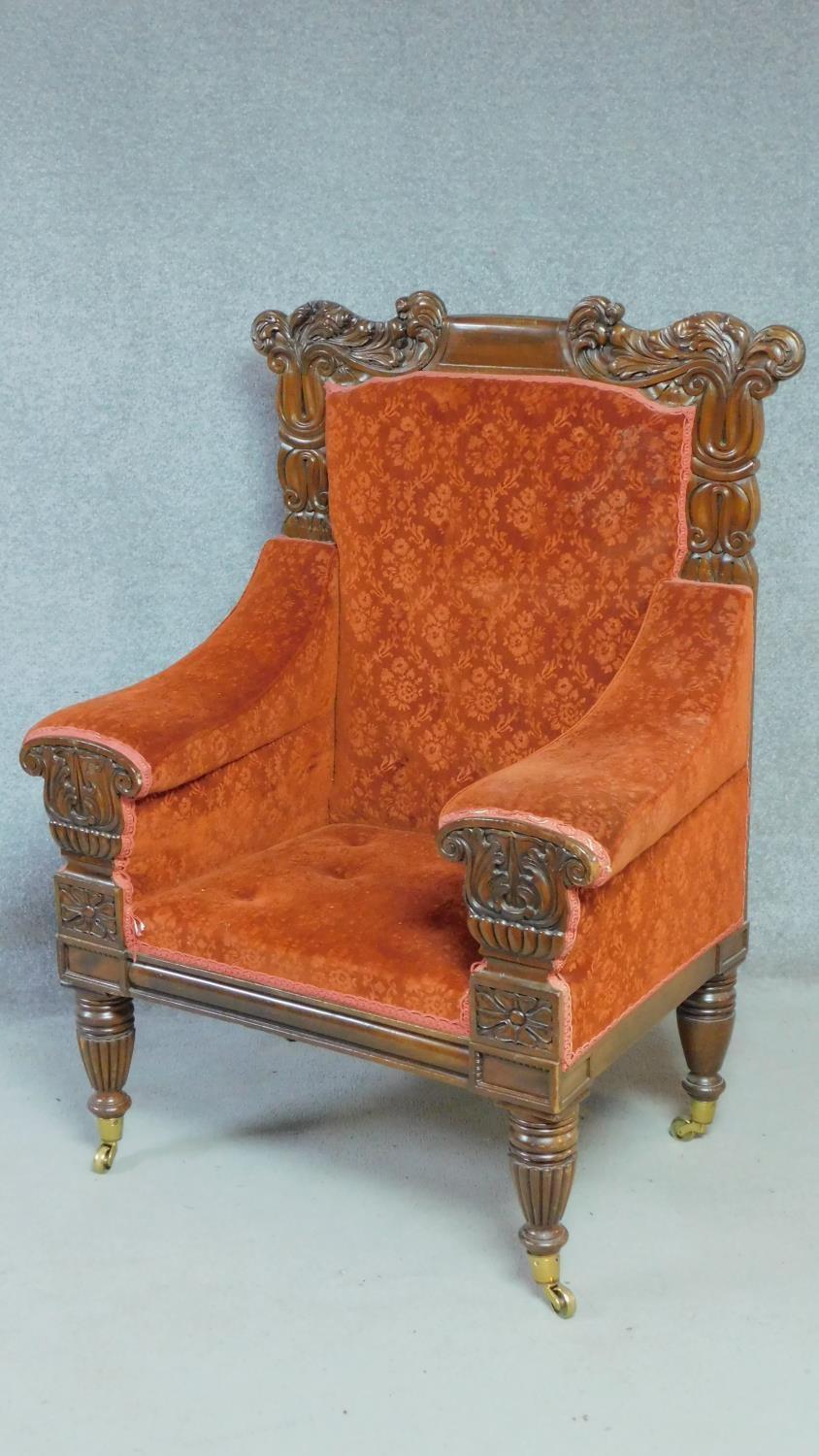 A large Regency mahogany carved throne chair in floral buttoned rouge upholstery on reeded tapering