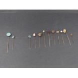 A collection of eleven antique silver, yellow metal and 9ct gold stick pins. Including a diamond