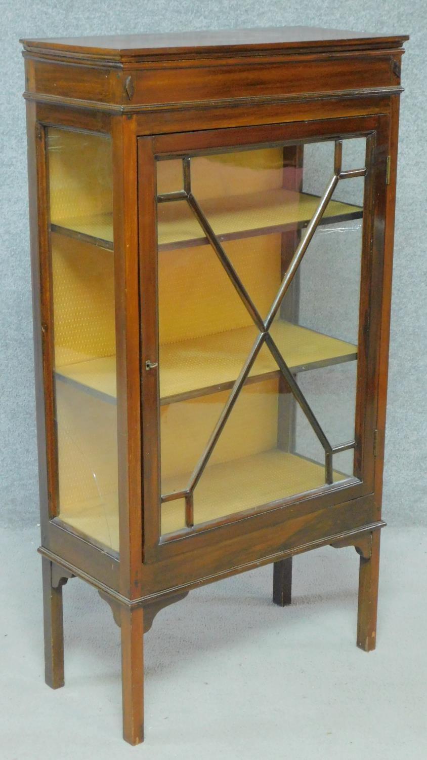 An Edwardian mahogany display cabinet with astragal glazed door enclosing display shelves on