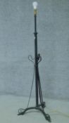 A cast iron scrolling form wrought iron tripod standard lamp. H.150cm