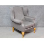 A Georgian style wing back armchair upholstered in pale grey velour on cabriole supports. H.108cm