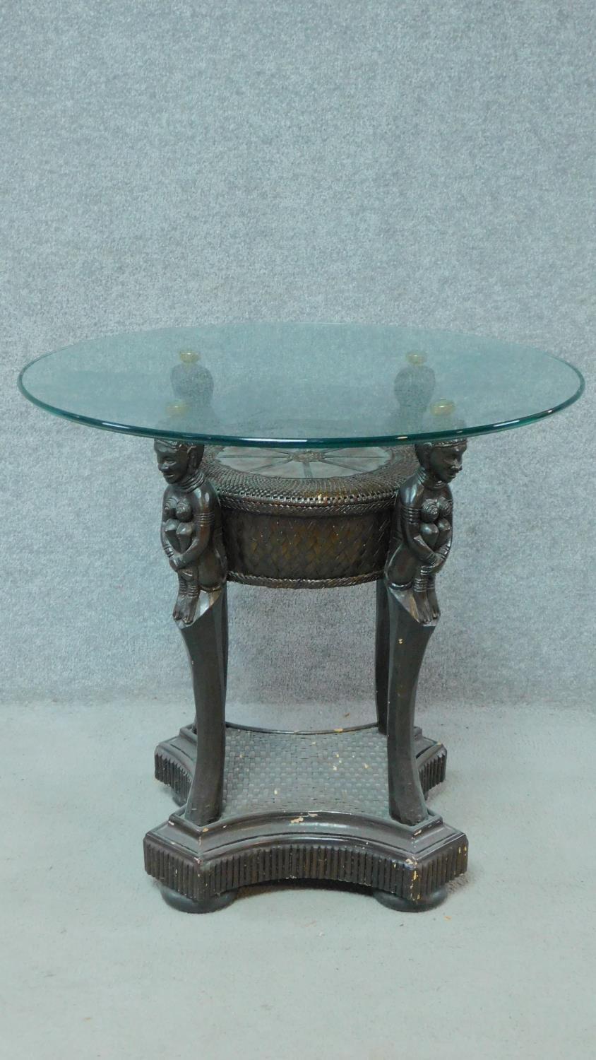 An Anglo African rattan glass top coffee table on figural supports. H.68 L.72 W.72cm