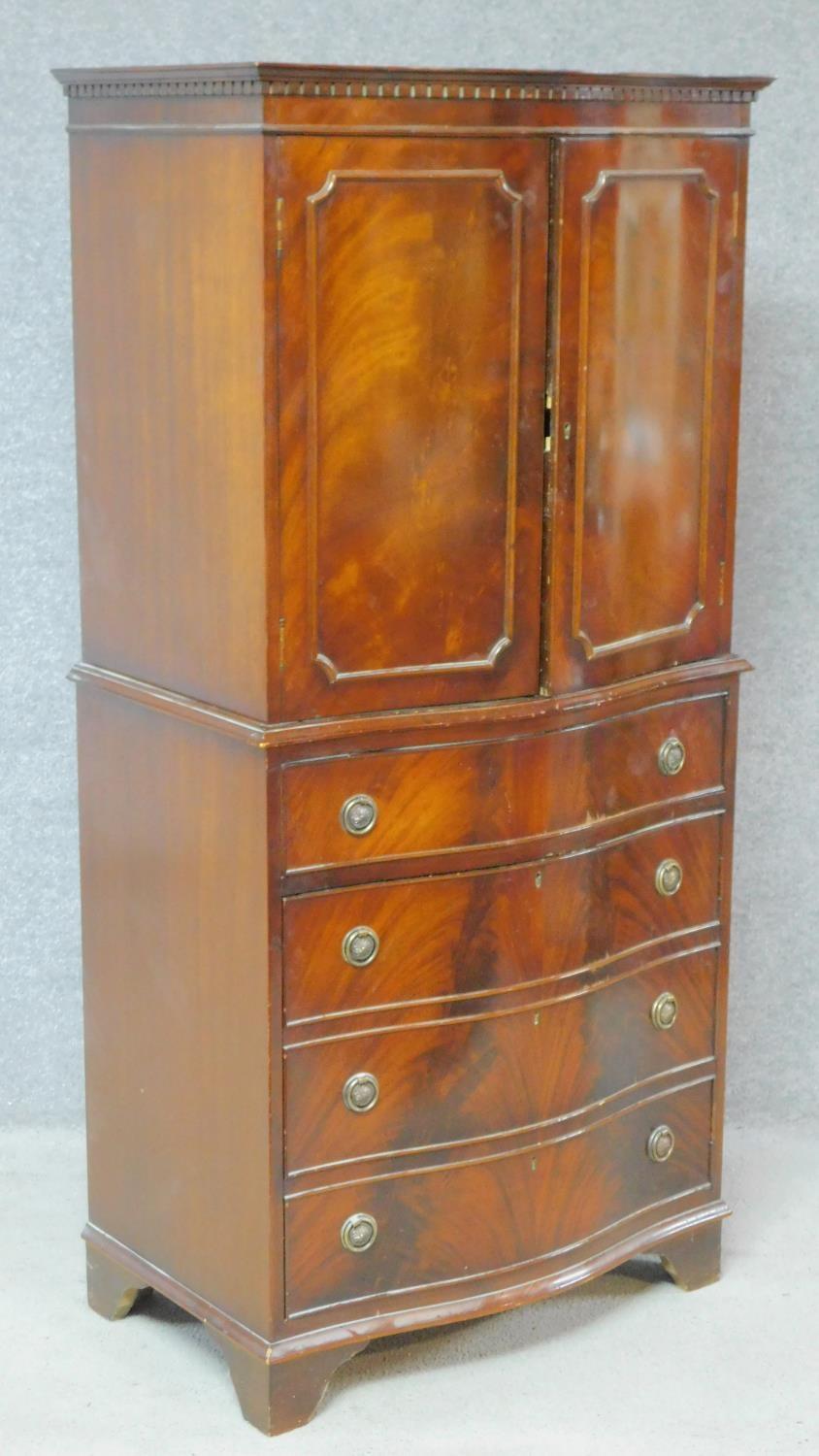 A Georgian style flame mahogany tallboy with panel doors enclosing shelves above drawer and panel