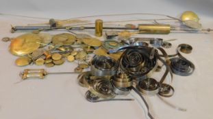 A collection of antique watch and clock parts, including brass pendulums, clock springs, a mercury