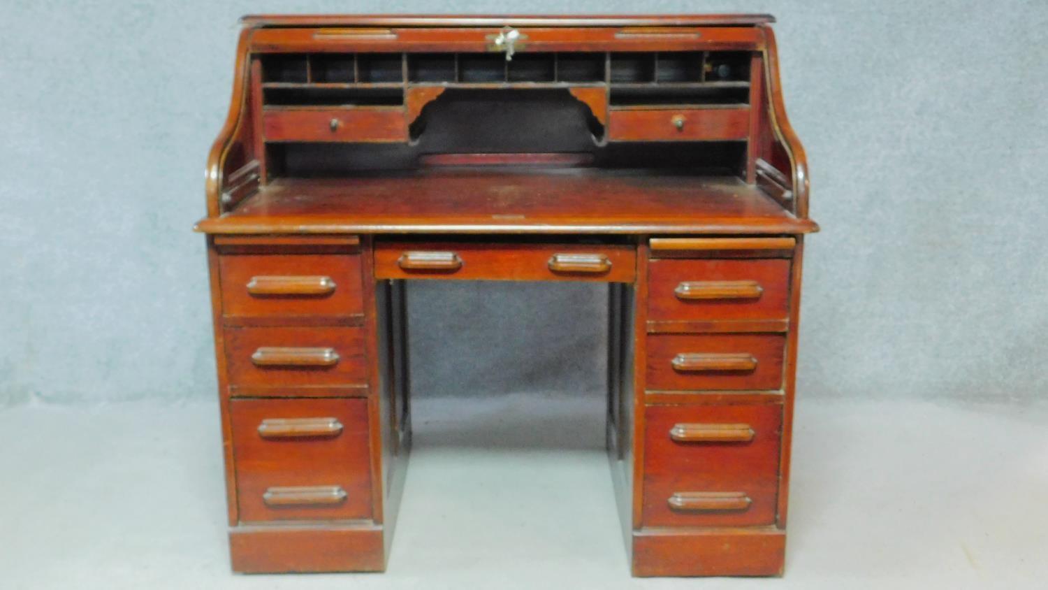 A late 19th century oak roll top desk with tambour shutter and fitted interior on twin pedestal base