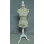 A mannequin on painted tripod base in a floral padded textile. H.134cm