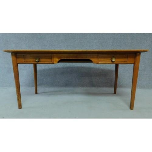 A mid 20th century teak writing table fitted inset tooled pale green leather top with two frieze