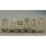 A set of six silver plated menu holders in the form of various of the classic antique style dining