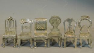 A set of six silver plated menu holders in the form of various of the classic antique style dining