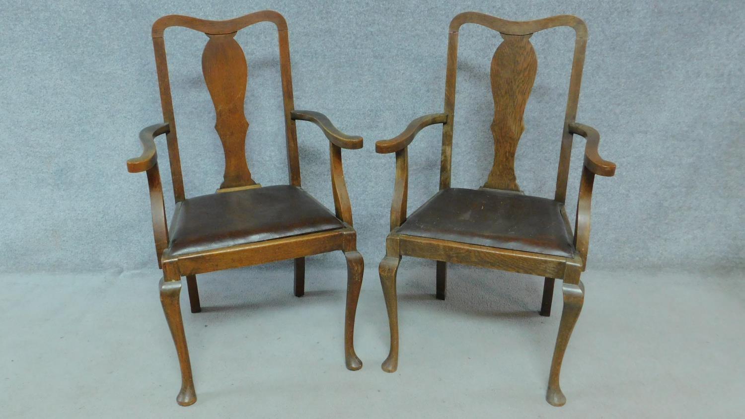A pair of Edwardian oak armchairs with leather drop in seats on cabriole supports. H.103cm