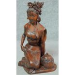 A 20th century Oriental carved wooden seated female figure with offering jar and floral head piece