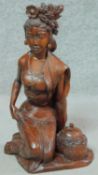 A 20th century Oriental carved wooden seated female figure with offering jar and floral head piece