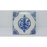 An 18th century Islamic blue and white hand painted ceramic tile with stylised floral design. 22x22