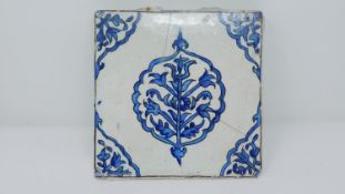 An 18th century Islamic blue and white hand painted ceramic tile with stylised floral design. 22x22