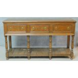A Georgian style country oak sideboard with three frieze drawers raised on turned supports united by