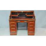 A late 19th century oak roll top desk with tambour shutter and fitted interior on twin pedestal base