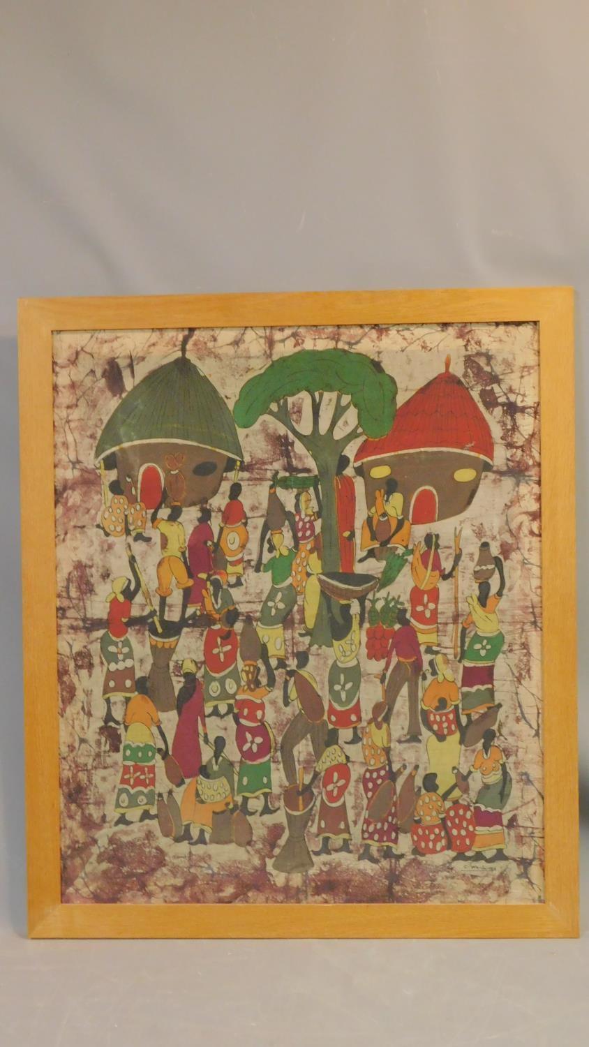 A framed African tribal batik depicting a tribal village. 78x91cm