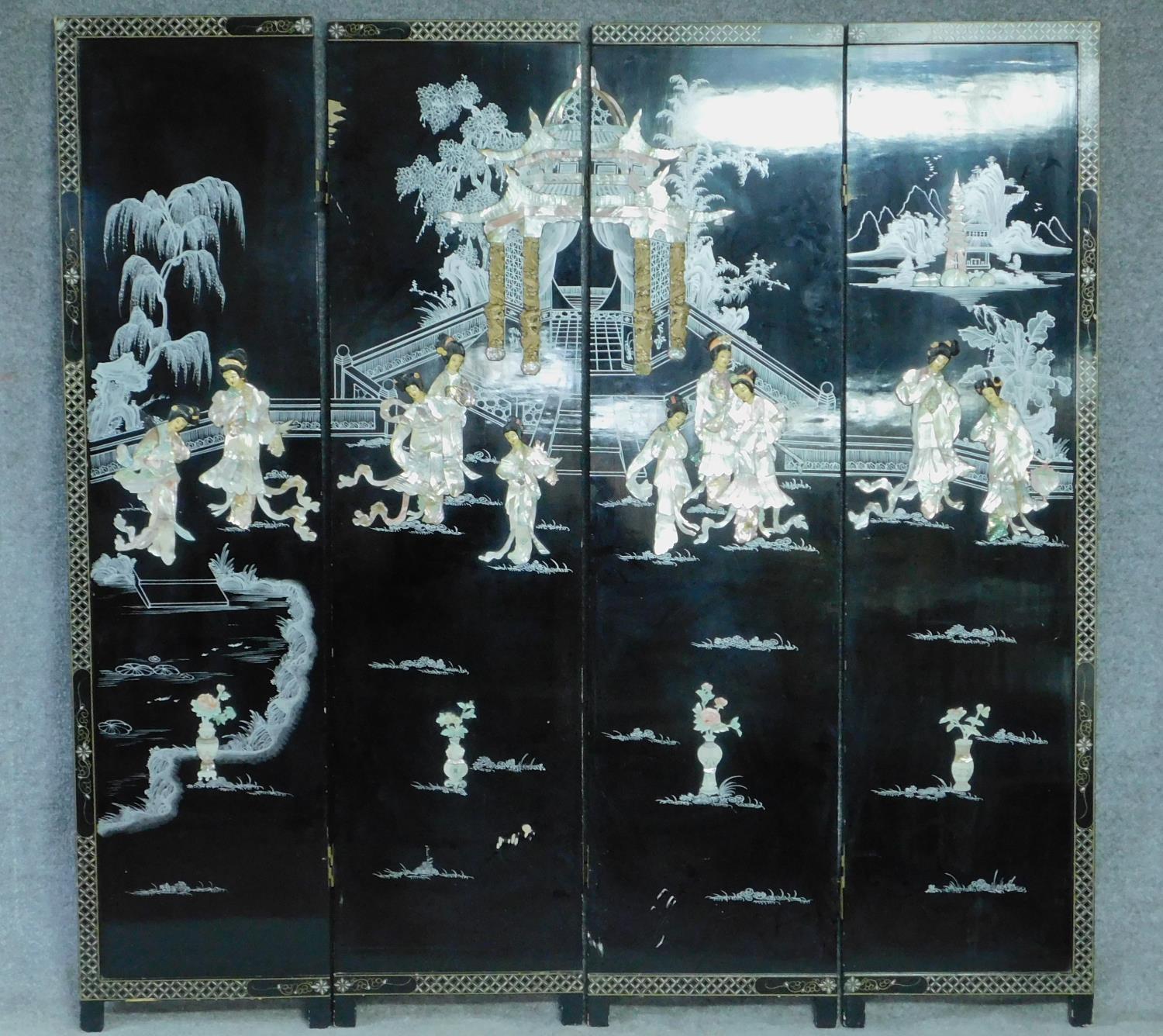 A Japanese black lacquered three fold and four panel screen with mother of pearl and bone inlay.