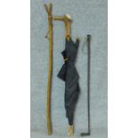 A vintage leather and braided chord riding crop along with a antler handled vintage black umbrella