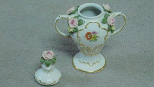 A German porcelain two handled lidded urn with hand painted floral motifs and sculpted porcelain