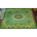 A large woollen carpet with central oval floral medallion on sage ground within floral border.