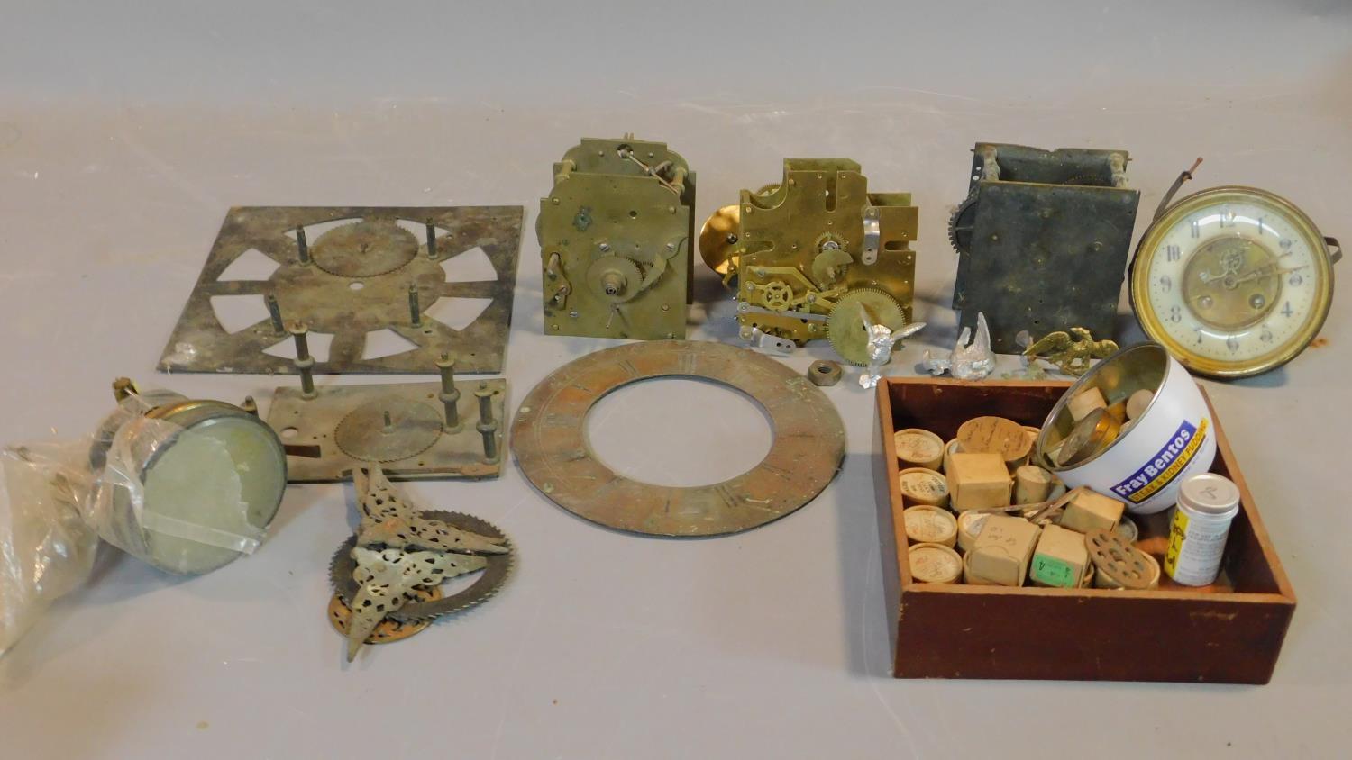 A collection of antique clock parts including clock movements, various clock dials and faces, a