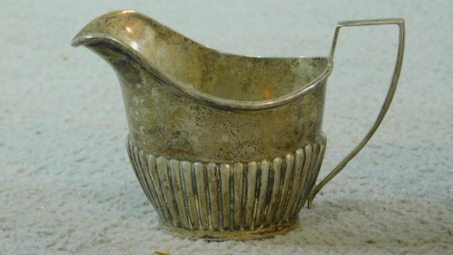 Three sterling silver items. Including an Art Deco milk jug on four button feet, hallmarked: EV - Image 2 of 11
