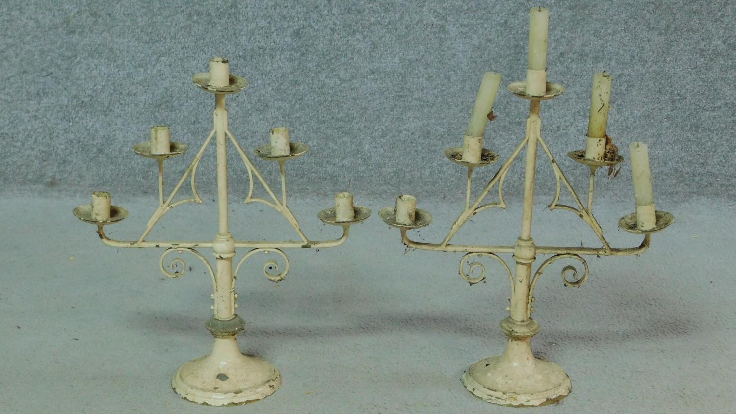 A pair of antique painted iron candelabras with a stylised foliate design. H.42cm