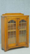 A mid 20th century oak bookcase with glazed doors enclosing shelves on bracket feet. H.99 W.79 D.