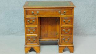 A Georgian style yewwood kneehole desk with inset tooled leather top, a central cupboard and an