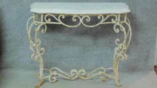 A mid 20th century white painted wrought iron console table with shaped marble top on scrolling